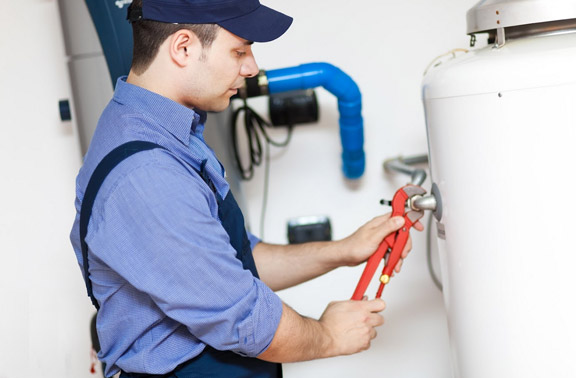 Tom is using an wrench to tighten a valve on a water heater repair in Coral Gables, FL