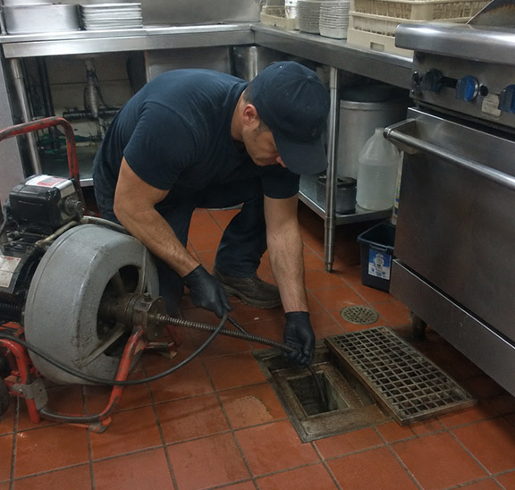 one of our plumbers is working on a commercial drain cleaning restaurant